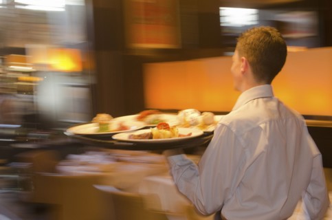 Waiter carrying tray with dishes through resturant