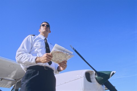 Low Angle Shot of a Pilot Holding a Map and Standing by a Private Propeller Plane