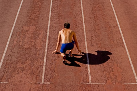 Runner on starting position of running track rear view