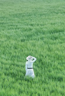Woman wearing hat standing in field rear view