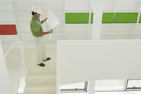 Male architect looking at plan in recently finished office building