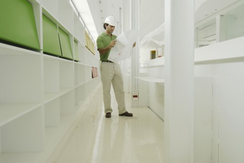 Male architect looking at plan in recently finished office building