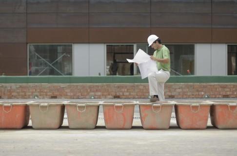 Engineer studying plan on construction site smiling profile