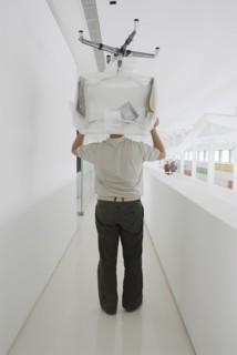Man carrying chair thorugh office rear view