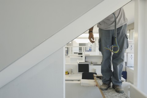 Workman installing electric cabling in new office low section
