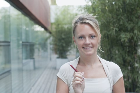 young woman hlding pen looking to camera