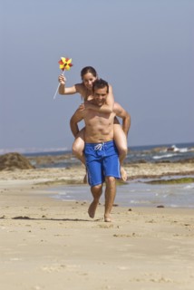 Man carrying woman on shoulders on beach