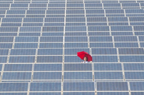 woman holding red umbrella in solar power plant