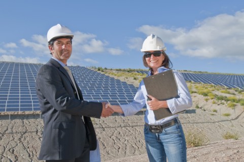 businessman shaking engineer's hand in solar plant