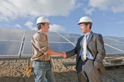 businessman shaking engineer's hand in solar plant
