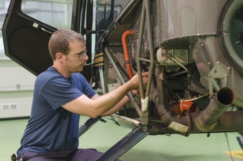 Hispanic mechanic working on helicopter in hangar
