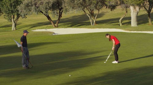 Caucasian couple putting on golf course