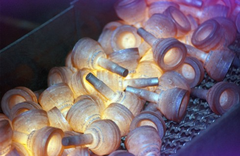 Glowing metal manufactured pieces on conveyor belt