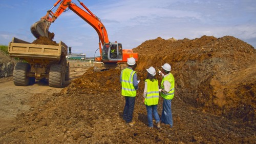 Workers watching digger machinery in field