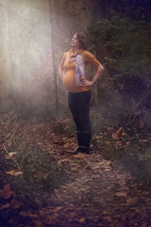 Pregnant Caucasian woman standing in forest
