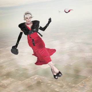 Woman in evening gown with glass of wine floating in sky