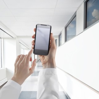 Businesswoman using cell phone in white corridor