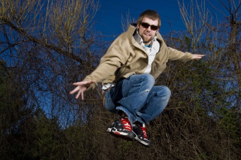 Man wearing sunglasses jumping for joy in forest