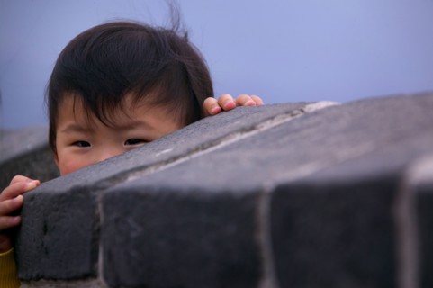 Eyes of boy peeking over stone wall