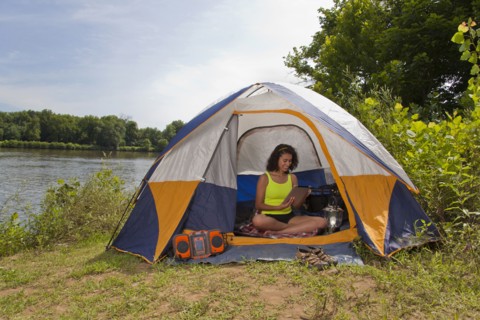 Hispanic woman using digital tablet in camping tent at lake