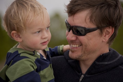 Caucasian father wearing sunglasses holding son