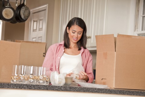 Smiling Hispanic woman packing dishes in kitchen