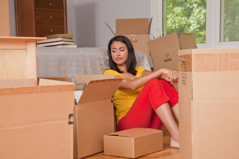 Hispanic woman sitting on floor with moving boxes