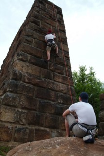Spotter watching friend climbing urban brick wall