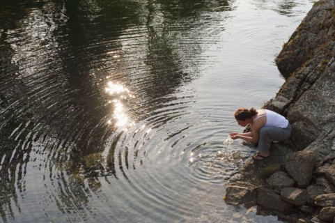 Hispanic woman washing face in lake