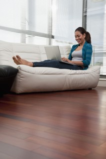 Hispanic woman on sofa using laptop