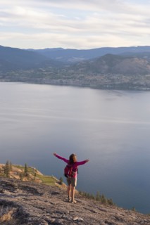Hispanic hiker standing on cliff over lake