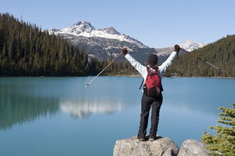 Hispanic hiker standing on rock near remote lake