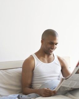 Man reading newspaper in bed