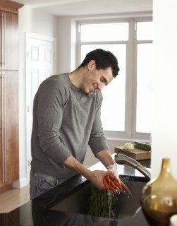 Man washing carrots and talking on telephone
