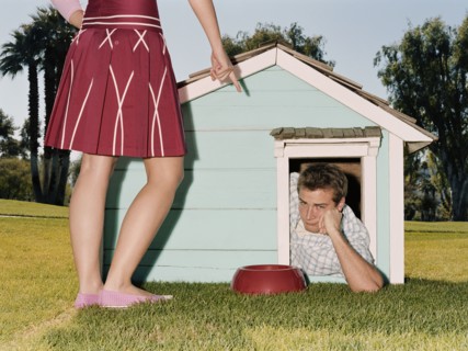 Frustrated man laying in doghouse