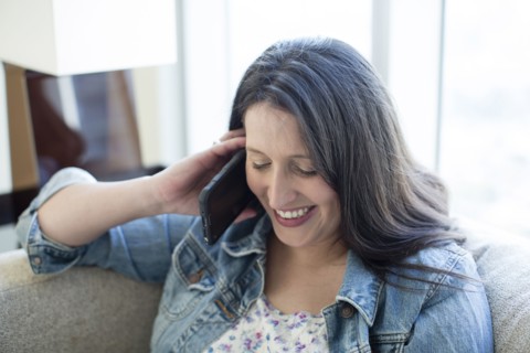 Hispanic woman talking on cell phone on sofa