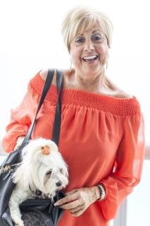 Older Caucasian woman carrying dog in purse