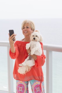Older Caucasian woman taking selfie with dog on balcony
