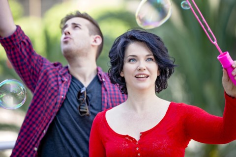 Caucasian couple blowing bubbles outdoors