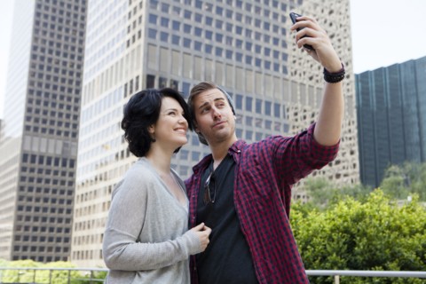 Caucasian couple taking selfie with cell phone in city