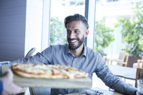 Server bringing diner pizza in restaurant