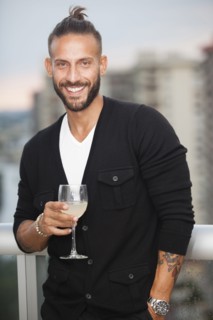 Hispanic man drinking wine on urban balcony