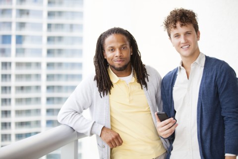 Businessmen using cell phone on urban balcony