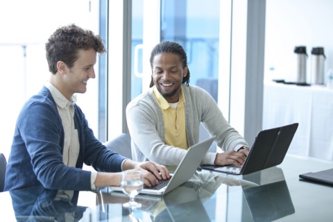 Businessmen working on laptops in office meeting
