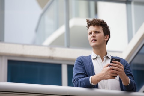 Caucasian businessman using cell phone on balcony