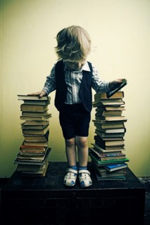 Boy holding cell phone near stacks of books