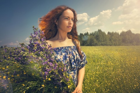 Caucasian woman holding flowers in rural field