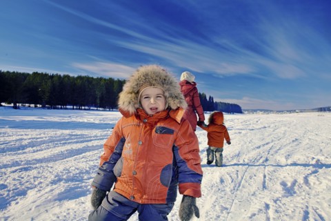 Mother and sons walking in snowy remote field