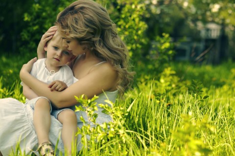 Caucasian mother holding son in grass