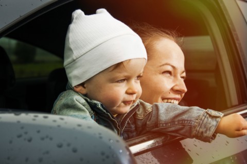 Caucasian mother and son looking out car window